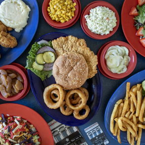 A colorful spread of fried chicken, burgers, onion rings, fries, and sides evokes comfort and joy in a festive atmosphere.