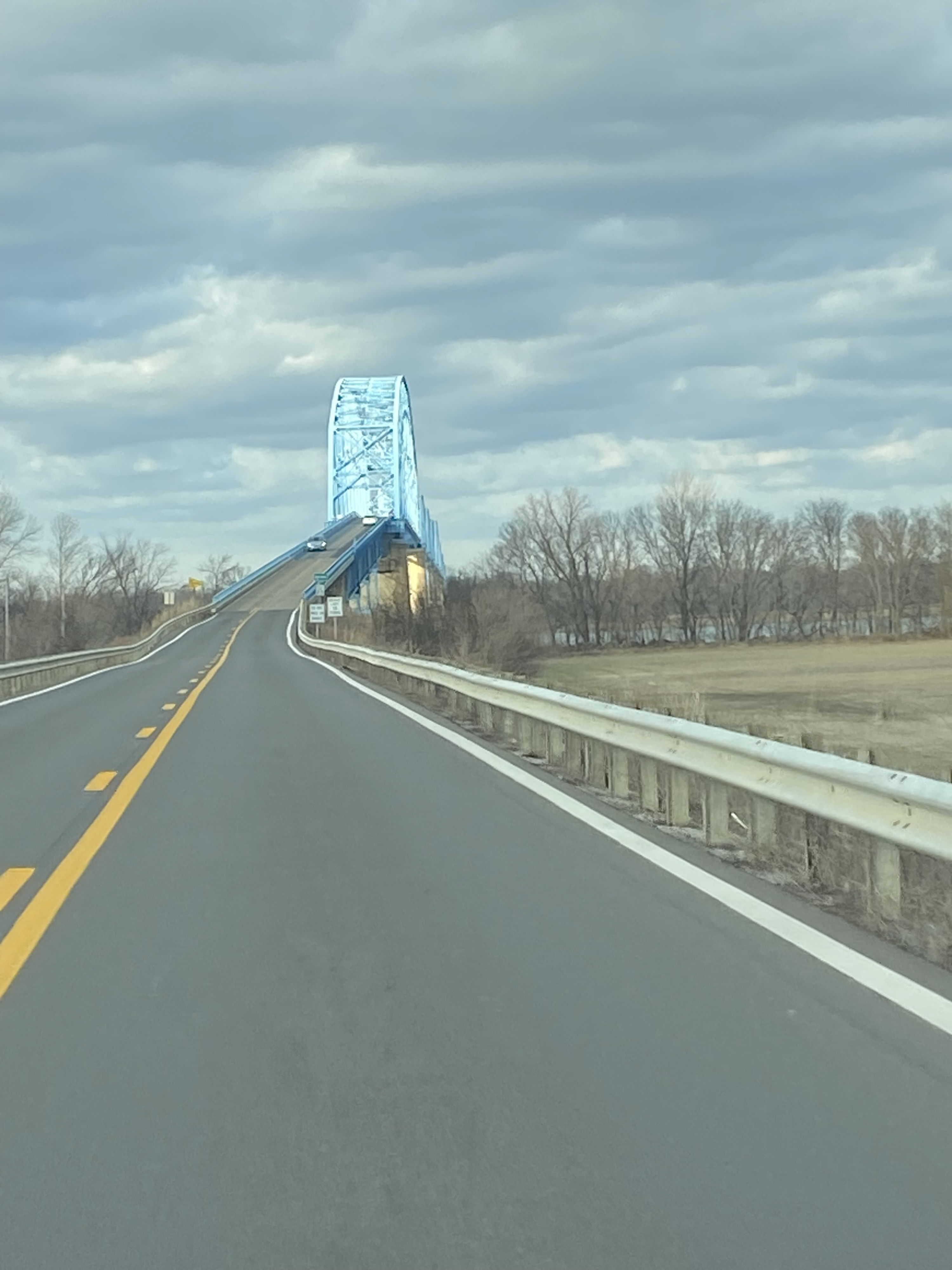 Empty highway under overcast skies, with a partially obscured structure, evoking feelings of isolation and introspection.