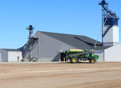 Large agricultural facility with a green tractor, conveying industriousness and modern farming against a clear blue sky.