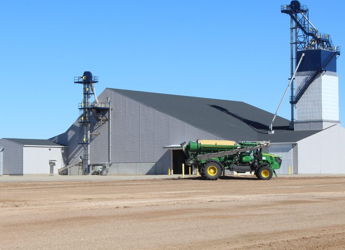 Large agricultural facility with a green tractor, conveying industriousness and modern farming against a clear blue sky.