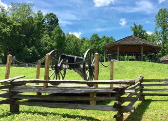 Serene outdoor scene with a grassy hill, gazebo, cannon, and lush greenery, evoking nostalgia and calmness.