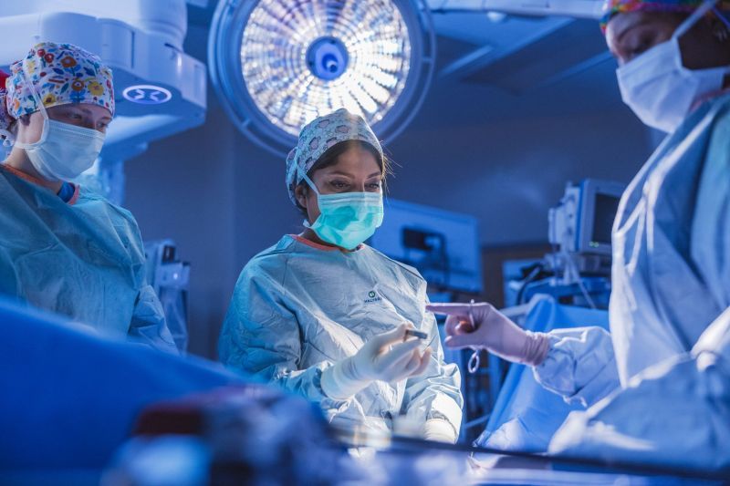 Surgical team in scrubs and masks focused on a procedure, embodying teamwork, intensity, and commitment to patient care.