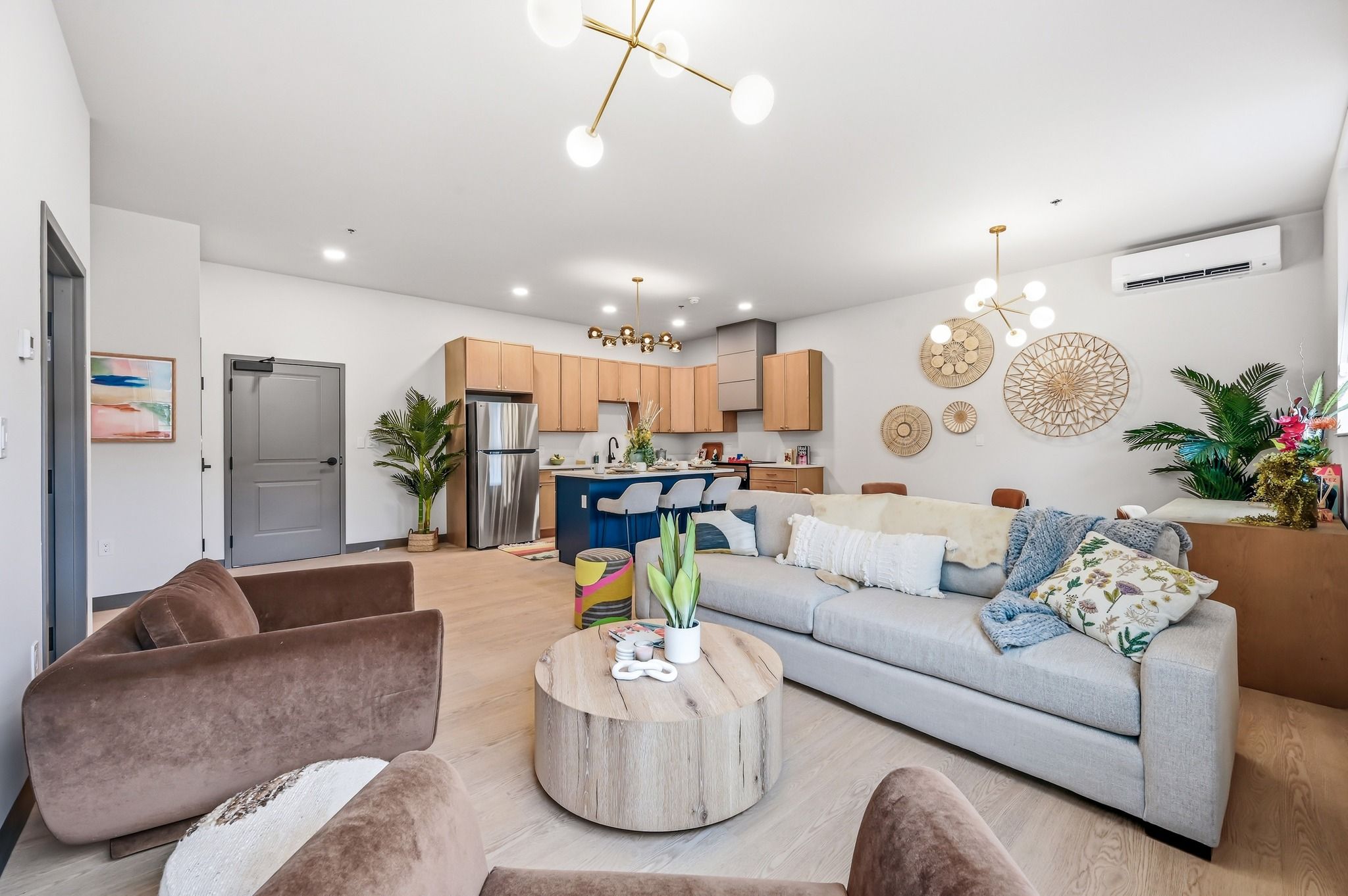 Modern living space with light sofa, brown armchairs, cozy decor, and inviting kitchen; evokes warmth and relaxation.