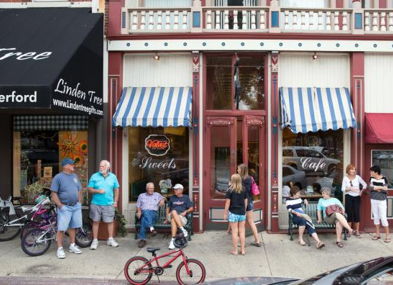 Charming street scene with people outside a vintage storefront, evoking community, nostalgia, and a relaxed atmosphere.