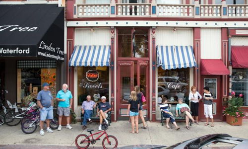 Charming street scene with people outside a vintage storefront, evoking community, nostalgia, and a relaxed atmosphere.