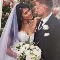 A joyful couple at their wedding share a loving gaze, surrounded by vibrant flowers, capturing love and celebration.