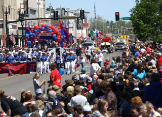 A lively parade with a large crowd, colorful decor, and enthusiastic participants, evoking joy and community spirit.