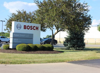 Outdoor scene with a "BOSCH" sign, manicured grass, trees, and clear skies, reflecting professionalism and inviting ambiance.