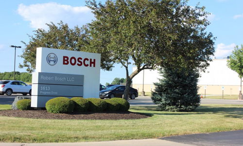Outdoor scene with a "BOSCH" sign, manicured grass, trees, and clear skies, reflecting professionalism and inviting ambiance.