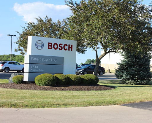 Outdoor scene with a "BOSCH" sign, manicured grass, trees, and clear skies, reflecting professionalism and inviting ambiance.