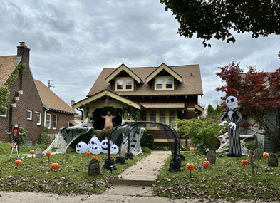 A Halloween-decorated house features inflatable figures, pumpkins, and cobwebs, creating a festive and playful spooky atmosphere.