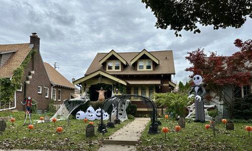 A Halloween-decorated house features inflatable figures, pumpkins, and cobwebs, creating a festive and playful spooky atmosphere.