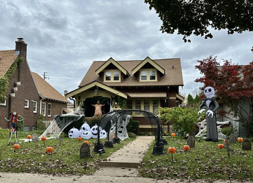 A Halloween-decorated house features inflatable figures, pumpkins, and cobwebs, creating a festive and playful spooky atmosphere.