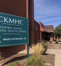 Entrance of Central Kansas Mental Health Center, featuring a welcoming environment with a clear sign and bright landscaping.