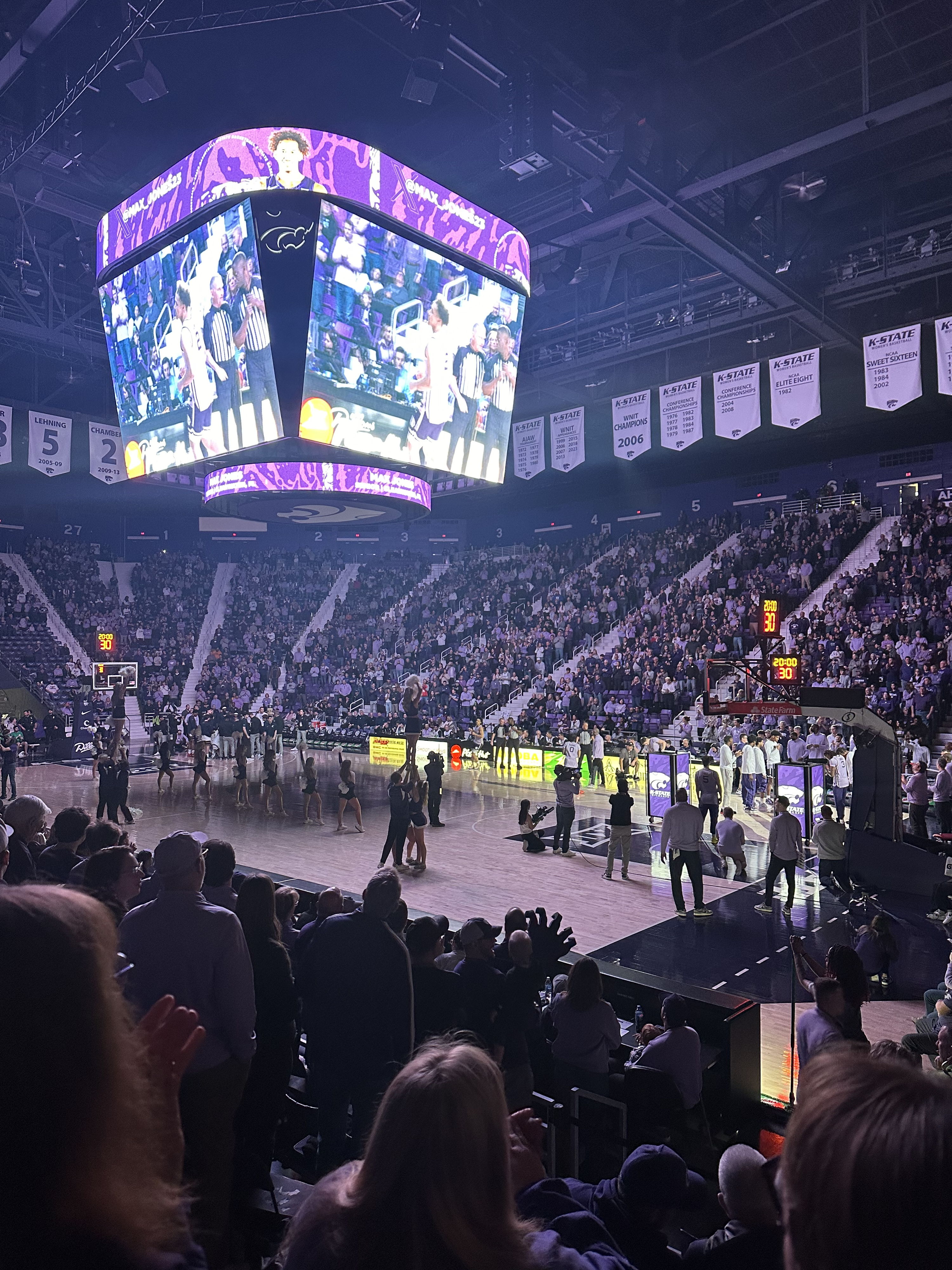 A lively sporting event scene with an engaged crowd, vibrant atmosphere, and a large scoreboard showing the action.