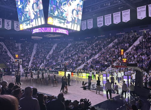 A lively sporting event scene with an engaged crowd, vibrant atmosphere, and a large scoreboard showing the action.