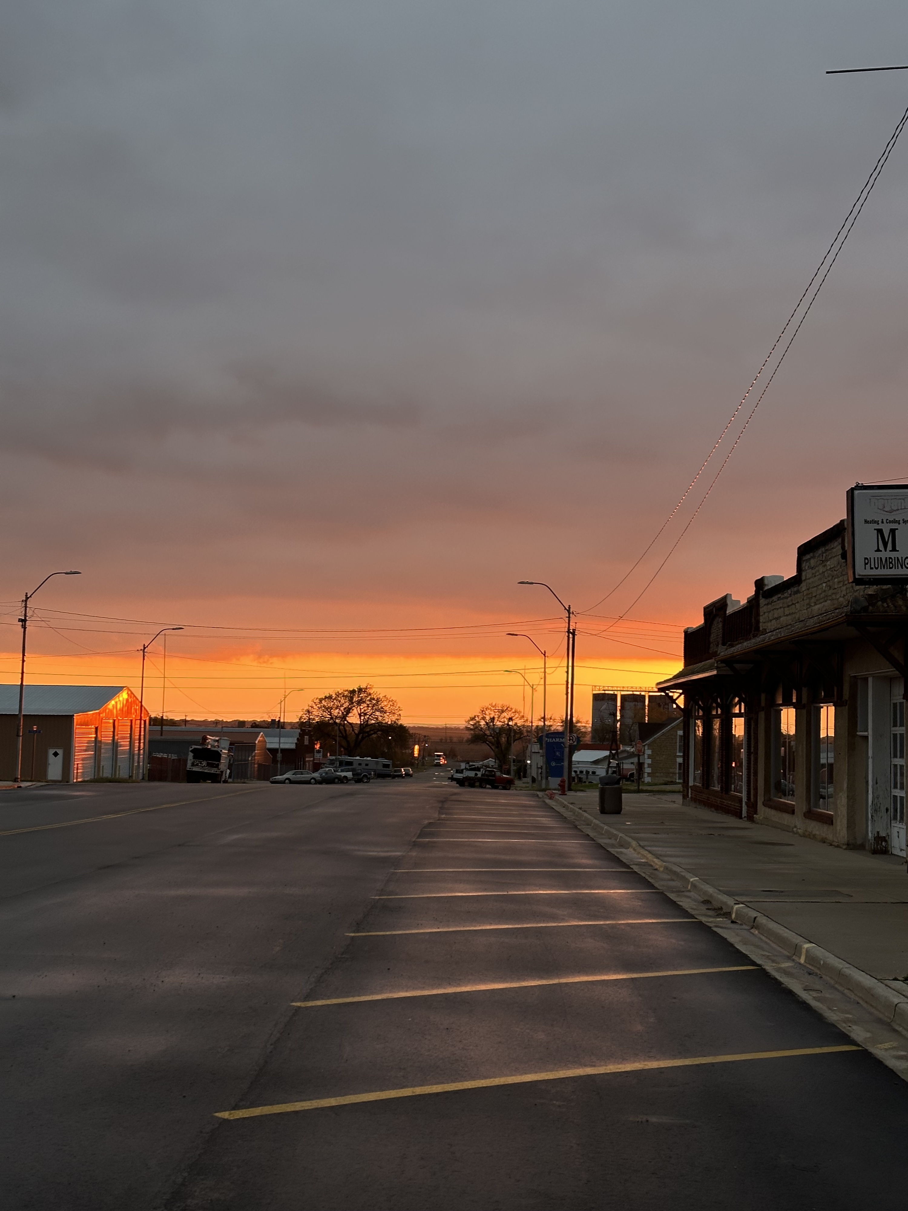 Dusk street scene with vibrant sunset; tranquil, reflective mood and empty surroundings evoke peace and contemplation.