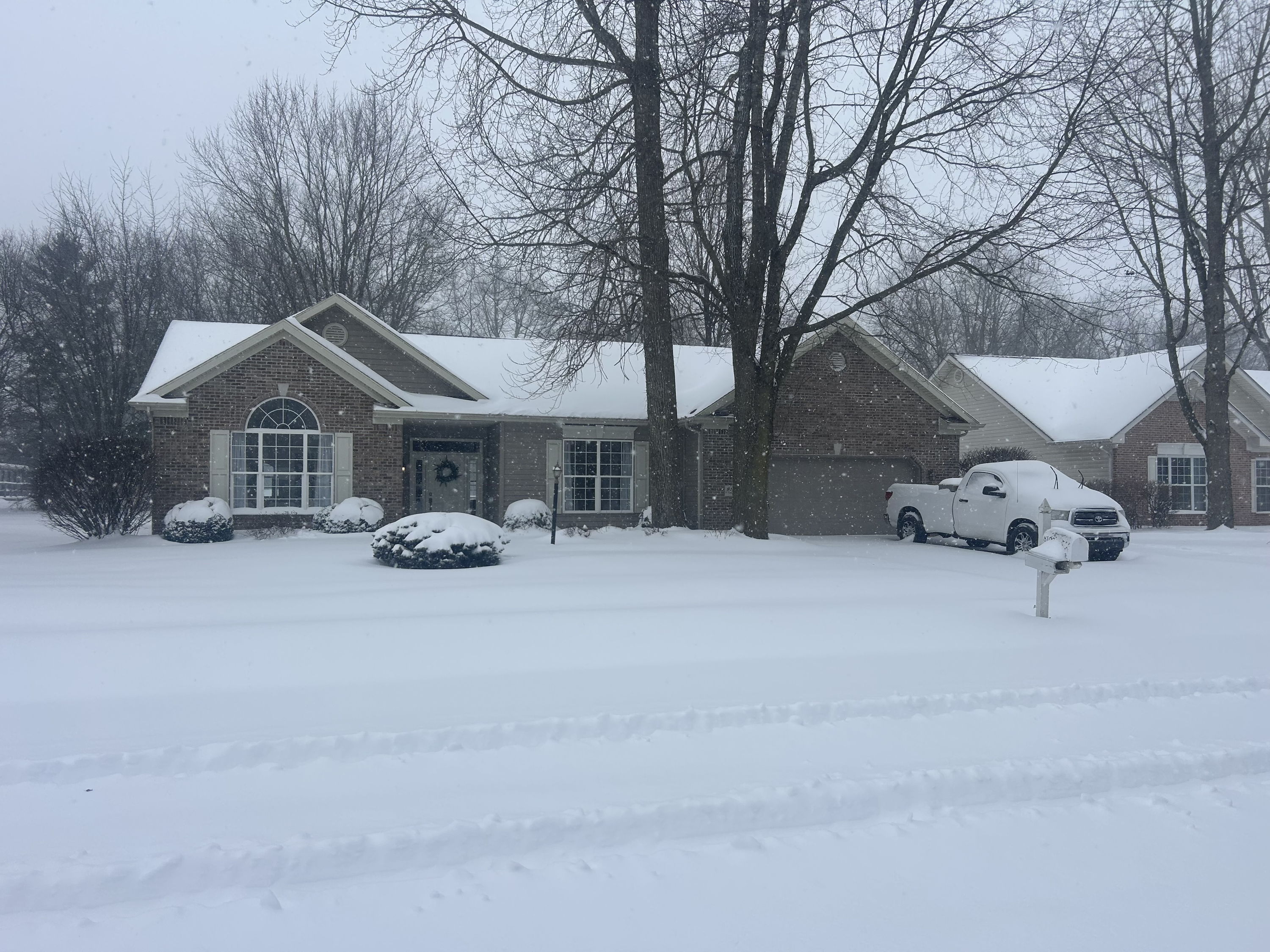 Cozy brick house in snowy scene with trees; evokes tranquility, warmth, and solitude amidst the winter landscape.