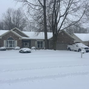 Cozy brick house in snowy scene with trees; evokes tranquility, warmth, and solitude amidst the winter landscape.