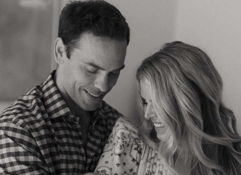 A warm black-and-white photo of two parents gazing lovingly at their newborn, capturing joy, love, and a bond of devotion.
