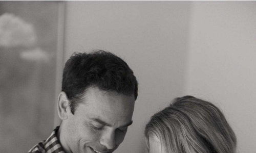 A warm black-and-white photo of two parents gazing lovingly at their newborn, capturing joy, love, and a bond of devotion.