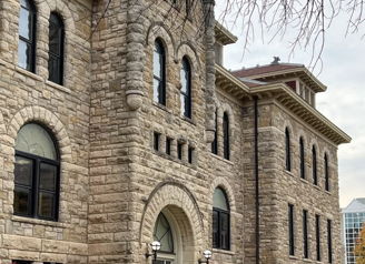 Historic stone building with arched windows, autumn foliage, overcast sky, evoking nostalgia and community.