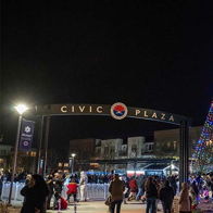 Vibrant night at Civic Plaza with a large, illuminated Christmas tree, joyful crowds, and festive, warm atmosphere.