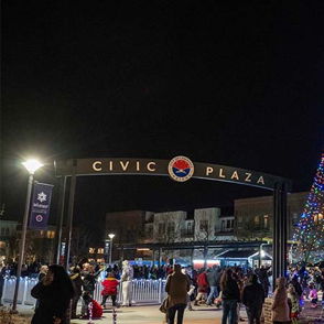 Vibrant night at Civic Plaza with a large, illuminated Christmas tree, joyful crowds, and festive, warm atmosphere.