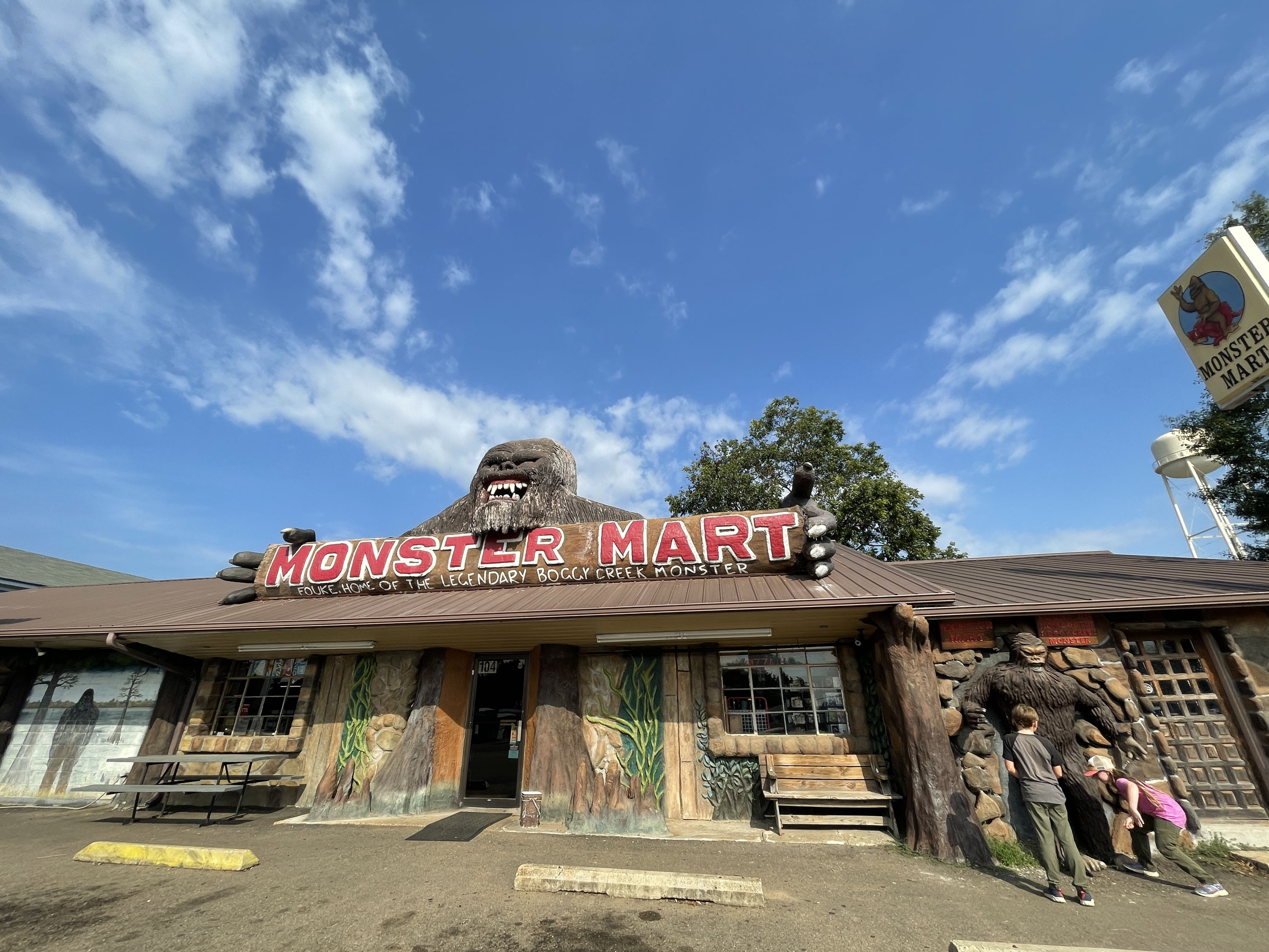 Whimsical "Monster Mart" storefront features a playful monster sculpture, vibrant red sign, and inviting atmosphere for families.