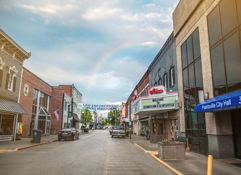 Charming street scene with mixed architecture, a rainbow, and a peaceful atmosphere, evoking nostalgia and tranquility.