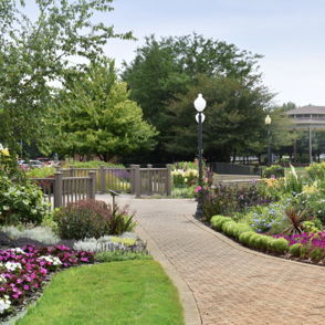 A serene garden path lined with colorful flowers, lush greenery, and a gazebo, creating a tranquil atmosphere.