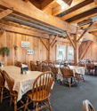Cozy restaurant with rustic wooden decor, warm lighting, inviting atmosphere, and tables ready for dining or quiet reflection.