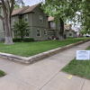 Residential area with a green lawn, trees, and a two-story house, conveying calmness and a peaceful neighborhood vibe.
