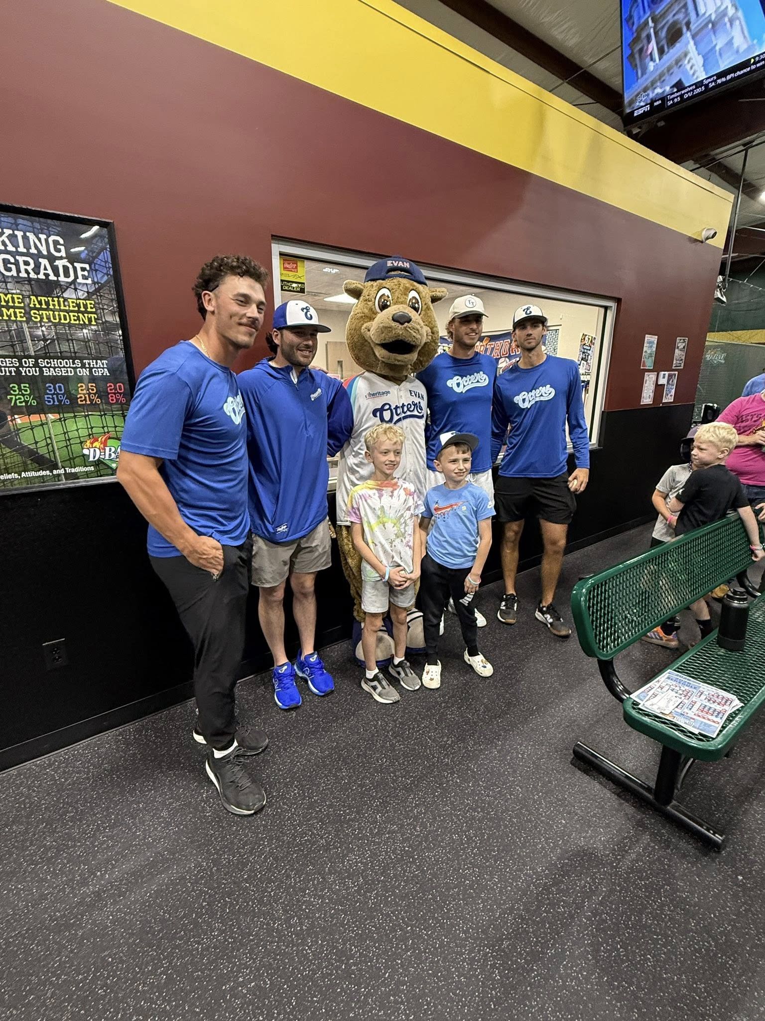 Cheerful group in blue shirts poses with a friendly mascot, radiating joy and community spirit at a fun event.