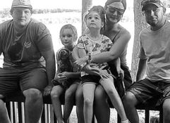 Five individuals sit casually on a railing by water, evoking joy, nostalgia, and a sense of calm camaraderie.