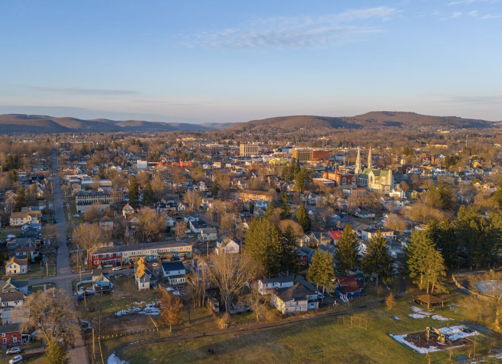 Aerial view of a charming small town with rolling hills, evoking tranquility, nostalgia, and a sense of community.