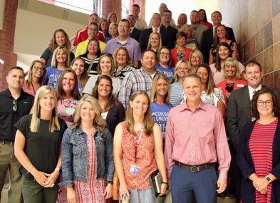 A happy group poses on a staircase, showcasing community, unity, and positivity in a professional yet relaxed atmosphere.