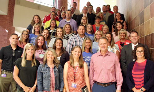 A happy group poses on a staircase, showcasing community, unity, and positivity in a professional yet relaxed atmosphere.