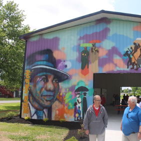Colorful mural showcasing community themes; two people walking by enhance the lively, inviting atmosphere of creativity.