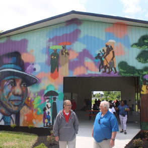 Colorful mural showcasing community themes; two people walking by enhance the lively, inviting atmosphere of creativity.