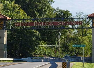 Ornate entrance sign of West Baden Springs, framed by lush greenery, exudes charm and invites exploration.