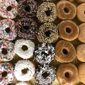 Colorful donuts in a grid, topped with sprinkles, chocolate, and glaze, evoke joy and nostalgia for sweet treats.