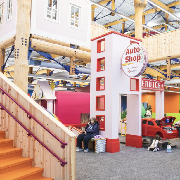 Vibrant indoor play area for children with colorful walls, play structures, and a themed "Auto Shop" for imaginative play.
