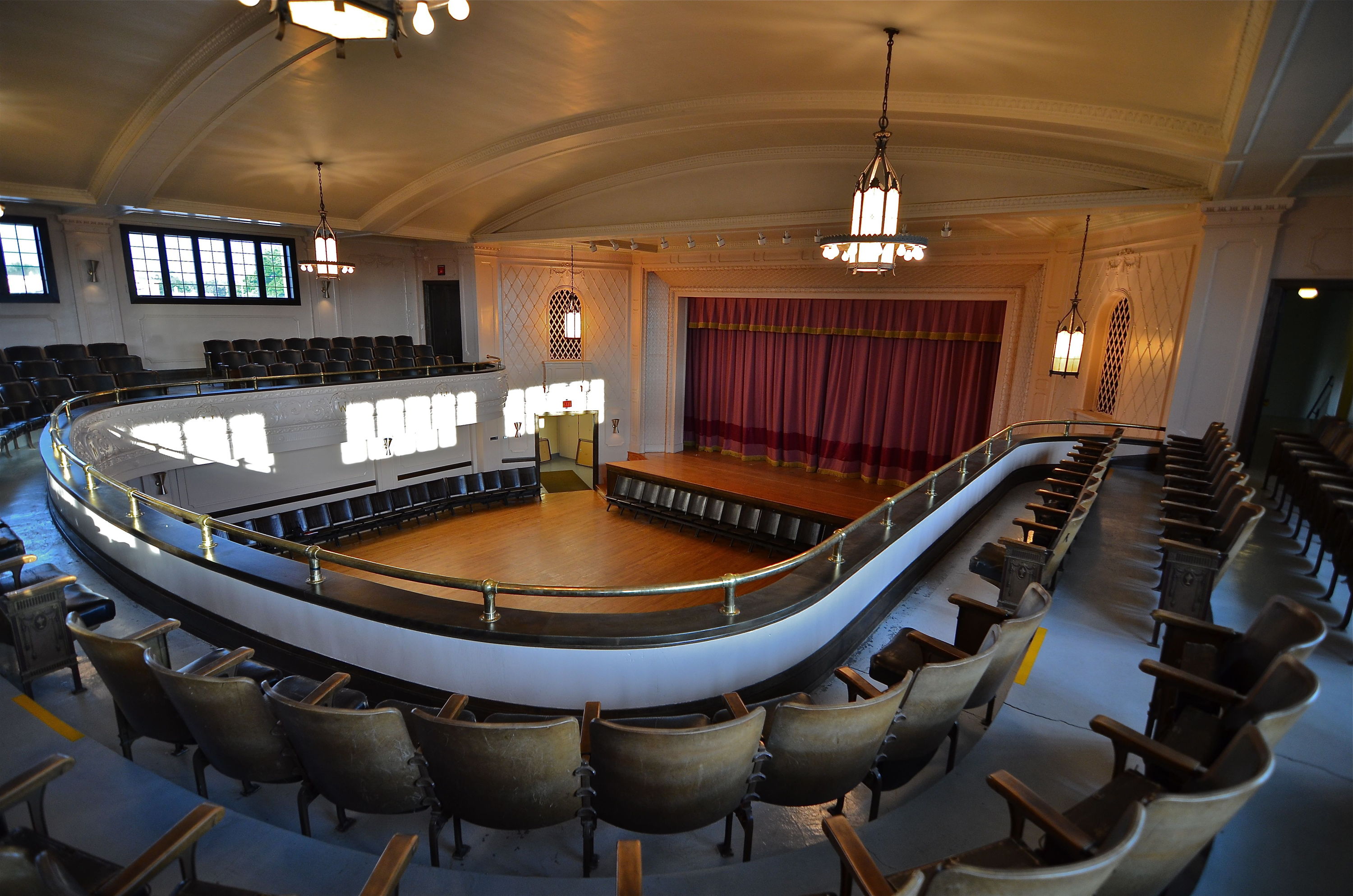 Elegant theater with tiered seating, central stage, red curtain, warm lighting, evoking nostalgia and anticipation for performances.