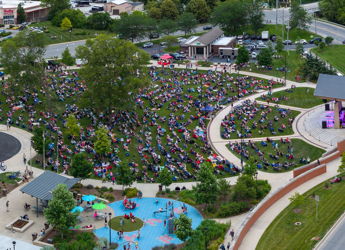 Large outdoor gathering in a park with people seated on grass, creating a joyful and community-focused atmosphere.