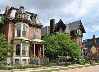Row of detailed historical houses with Victorian styles, lush greenery, and an overcast sky, evoking nostalgia and history.
