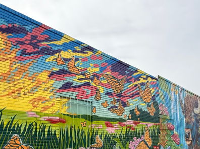 Vibrant mural of butterflies and flowers in a bright landscape, evoking joy, freedom, and a connection to nature.