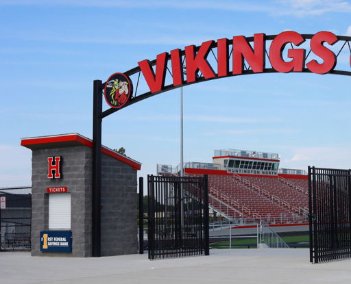 Entrance of a sports venue with a "VIKINGS" sign, ticket booths, and energetic colors, evoking community pride and excitement.