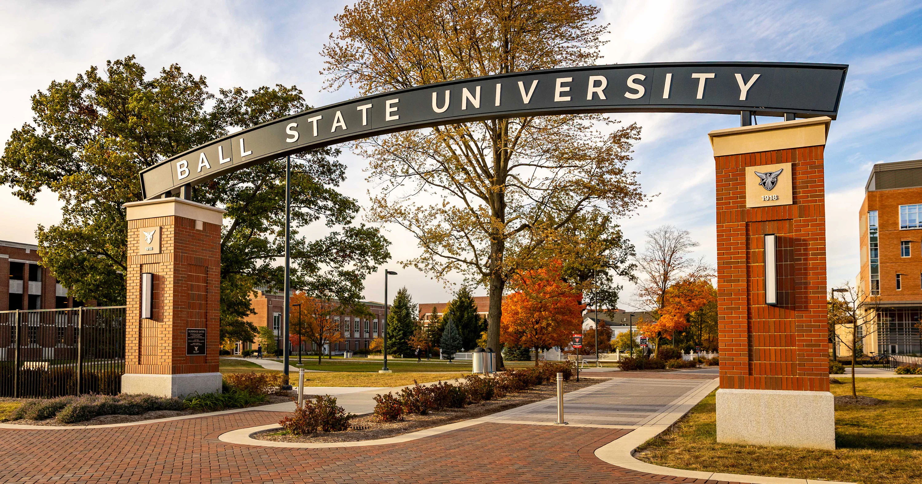 Welcoming entrance to Ball State University with an archway, pathways, trees, and vibrant campus, evoking openness and enthusiasm.