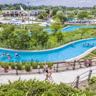 A vibrant water park scene with a lazy river, greenery, and people enjoying summer fun, evoking joy and relaxation.
